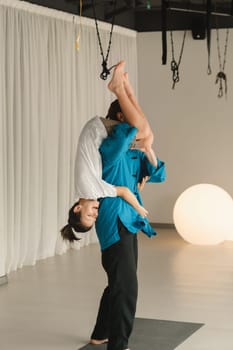 Yoga instructor in training messing with a child holding on his shoulders in the gym.