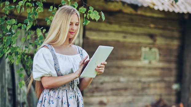 Village Slavic girl flipping a tablet in the countryside