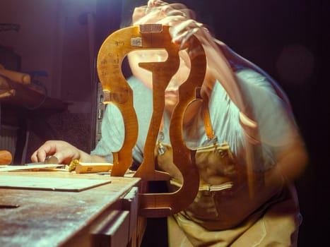 luthier violin maker luthier working with violin mould on center bot, corner blocks , bend ribs for a new classic handmade violin using mold long exposure blended frames.