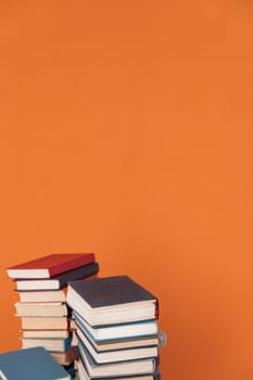 Stacks of books on orange background of school university library