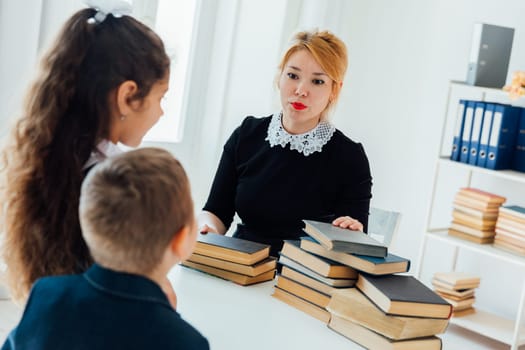 Teacher at lesson at school with children and books