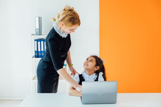 Teacher teaching girl on computer at school