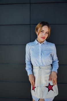 Beautiful fashionable woman standing against dark brick textured wall walk