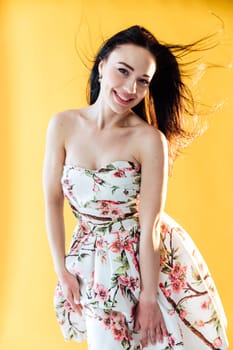 brunette in a floral dress on a yellow background