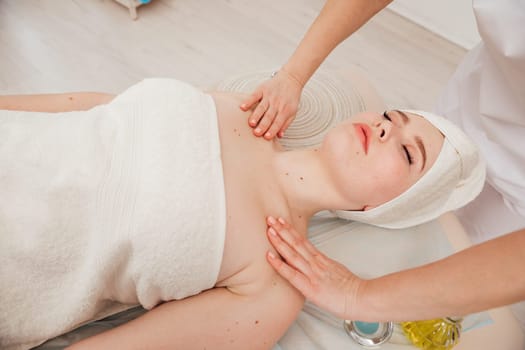 A cosmetologist woman massages the face of a client