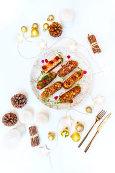 Eclairs on a marble plate on a background with Christmas or New Year decor. High quality photo