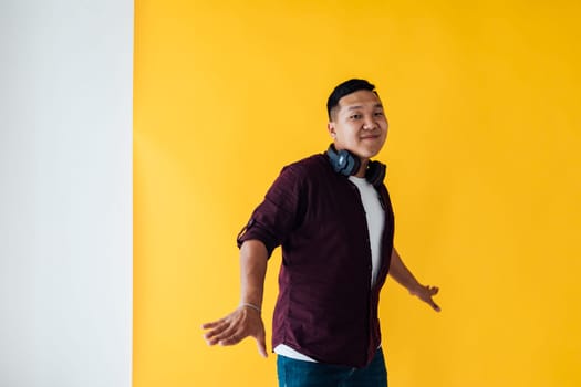A man with headphones dancing on a yellow background