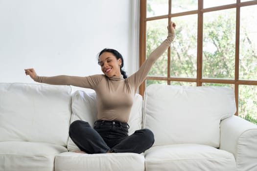 Young African American woman stretching arms for crucial relaxation at home. The happy woman spending weekend morning at living room.
