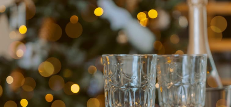 Champagne glasses, New Year decor. New Year's festive setting, family holidays.Two glasses of champagne are on the table against the background of New Year's decorated tree