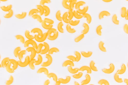 Scattered Uncooked Chifferi Rigati Pasta on White Background. Fat and Unhealthy Food. Classic Dry Macaroni Texture. Italian Culture and Cuisine. Raw Pasta