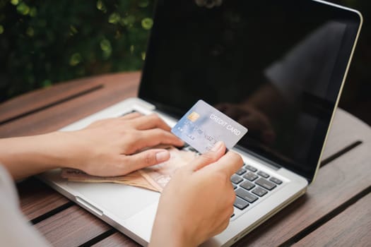 Woman using working and shopping, Online e-commerce, internet banking, Hands of businesswoman holding thai money and credit card on laptop computer, technology finance