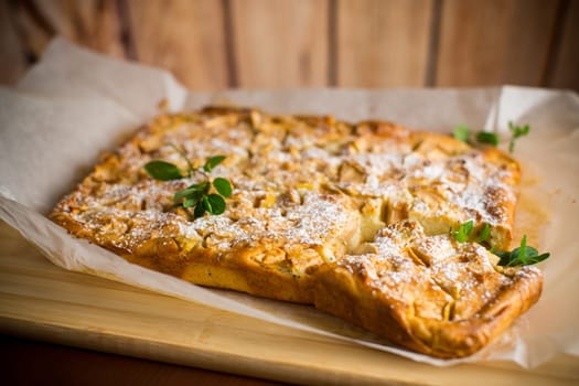 prepared curd semolina pie with quince inside and covered with powdered sugar on a wooden board.