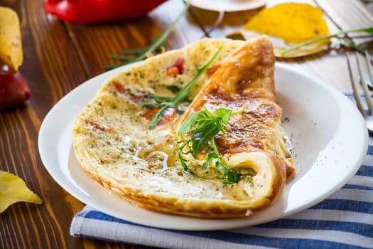 Fried omelettes with various autumn vegetables in a plate on a wooden table. Autumn recipes.