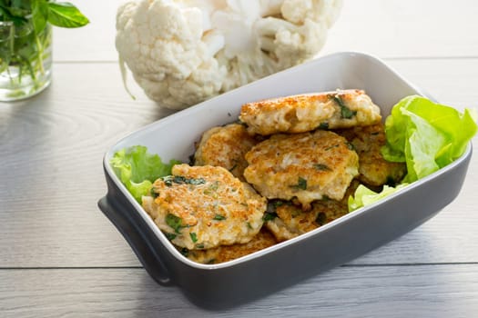 cooked vegetarian fried cauliflower cutlets in a ceramic form on a wooden table.