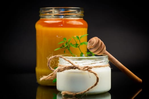 jar with natural homemade yogurt and delicious organic honey, isolated on a black background.