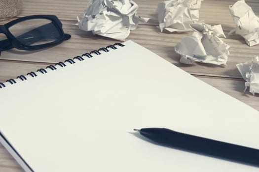 Notepad with trash paper background on wooden desk. Copy space.