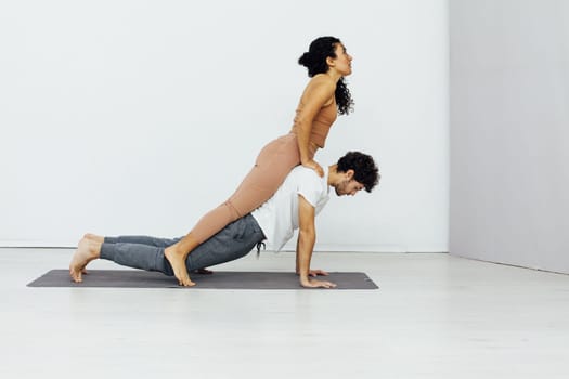 Smiling couple doing yoga exercises outdoors at the beach pier