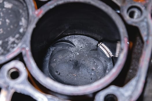 Close-up of a damaged piston of an internal combustion engine with carbon deposits in the cylinder block of a faulty engine. Pieces of metal broken off from the piston