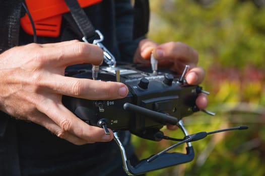 Close-up of a man's hands holding a transmitter and control equipment for an FPV drone quadcopter. Drone control concept.