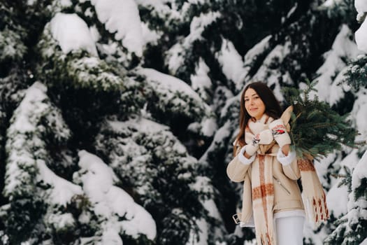 A girl in a winter forest with a bouquet of fir branches. Snowy winter.