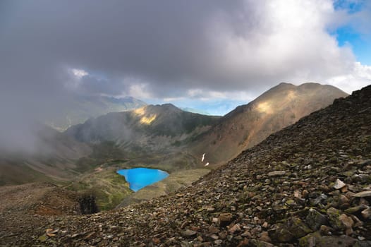 View on the turquoise color lake between high and rocky mountains. Beautiful alpine landscape.