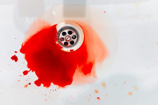splashes of blood and water flow into a white sink. pool of blood close-up, accident in the bathroom.