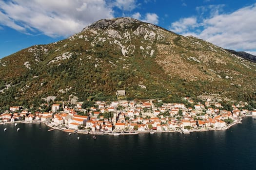 Winding coastline of Perast with the bell tower of the church at the foot of the mountain. Montenegro. Drone. High quality photo
