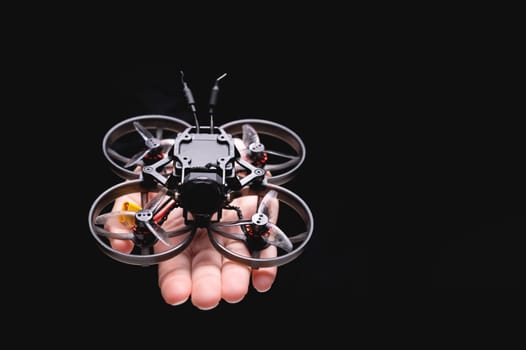 A woman holds a racing drone in her hands, showing it to the camera on her palm. Close-up of a hobby toy.