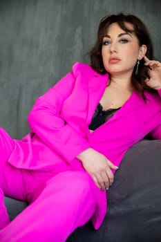 Portrait of a beautiful young woman in a purple business suit on a chair