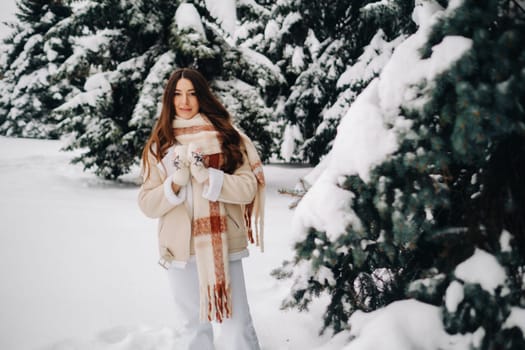 Portrait of a girl with long hair in mittens in a winter forest . Snowy winter.