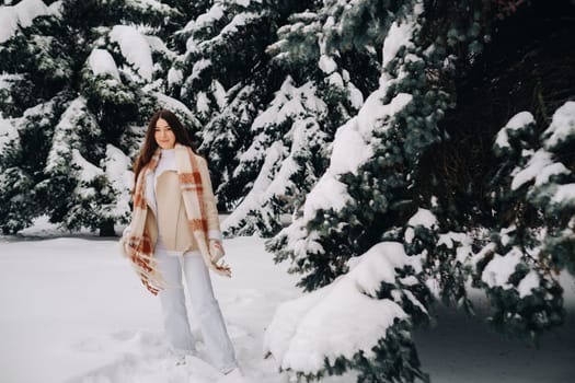 Portrait of a girl with long hair in mittens in a winter forest . Snowy winter.