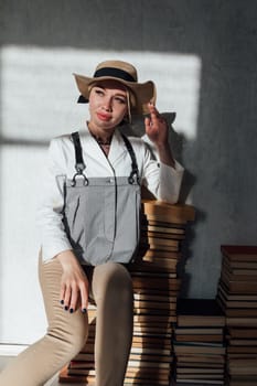 Woman sitting on a floor and holding book in front of face on pink background