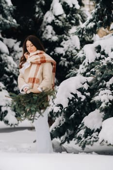 A girl in a winter forest with a bouquet of fir branches. Snowy winter.