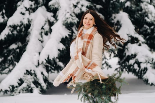 A girl in a winter forest with a bouquet of fir branches. Snowy winter.