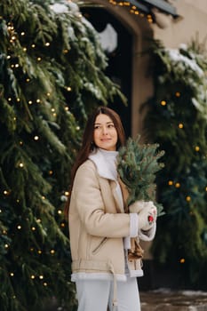 A girl with long hair in winter on the street with a bouquet of fresh fir branches.