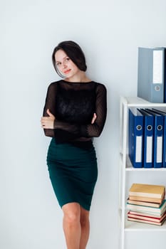 Woman in business suit standing at rack with folders and books in office
