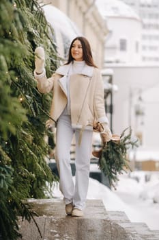 A girl with long hair in winter on the street with a bouquet of fresh fir branches.