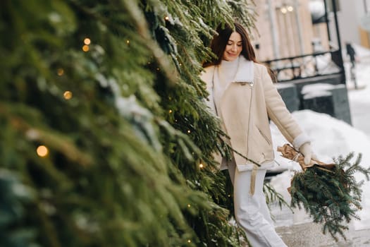 A girl with long hair in winter on the street with a bouquet of fresh fir branches.