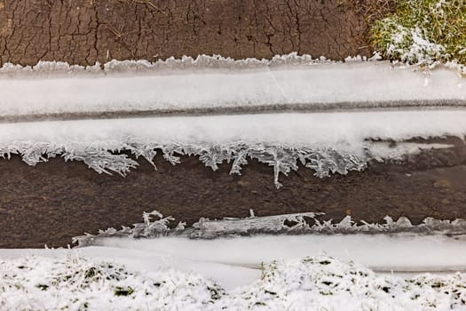 A stream bank with filigree crystals and formations of frozen water and ice