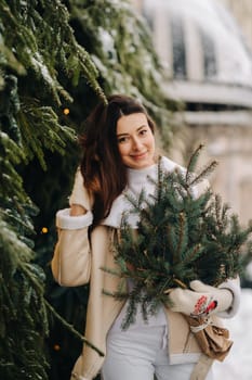 A girl with long hair in winter on the street with a bouquet of fresh fir branches.