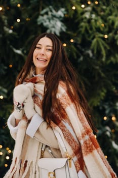 A girl with long hair in a scarf and with a white handbag walks down the street in winter.