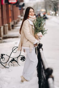 Girl with long hair in winter on the street with a bouquet of fresh spruce branches.