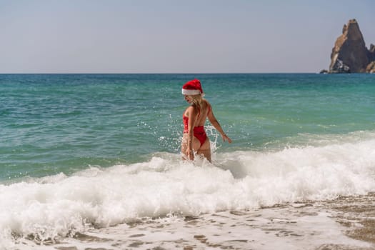 A woman in Santa hat on the seashore, dressed in a red swimsuit. New Year's celebration in a hot country.