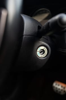 Close-up of a car ignition keyhole with a blurred dashboard background
