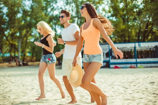 Young funny guys in sunglasses on the beach. Friends together. Summer bar is on background.