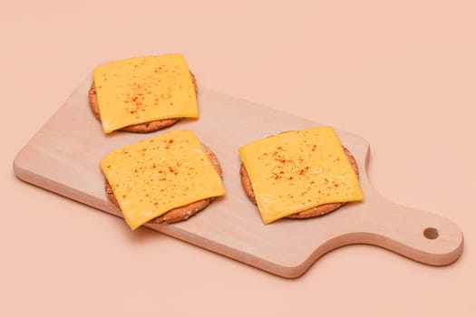 Crispy Cracker Sandwiches with Cheese and Paprika on Wooden Cutting Board and Beige Background