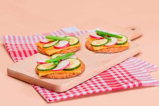 Light Breakfast. Quick and Healthy Sandwich. Fresh Cucumber and Radish with Green Onions and Cheese on Crispy Cracker on Wooden Cutting Board