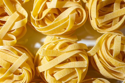 Uncooked Egg-Based Fettuccine Pasta: A Culinary Canvas of Ribbon-Shaped Macaroni, Creating a Lively and Textured Background for Gourmet Cooking. Dry Pasta. Raw Macaroni - Top View, Flat Lay