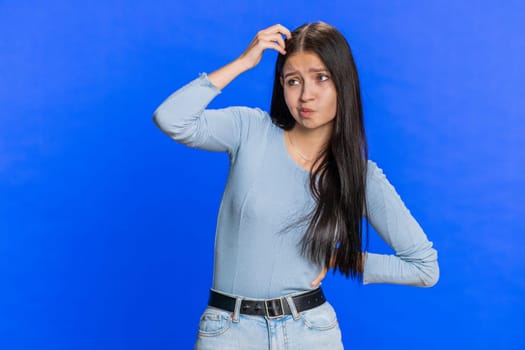 I don't know what to say. Confused Caucasian young woman feeling embarrassed about ambiguous question, having doubts, no answer, idea, being clueless, uncertain. Teen girl isolated on blue background