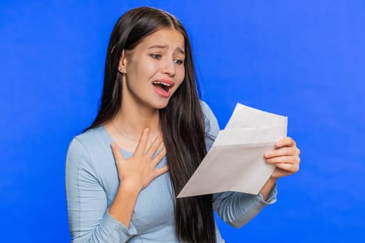 Excited young woman open envelope take out letter reads it feel happy. Career growth advance promotion, bank loan approve, monetary award long-awaited invitation great news. Pretty adult girl on blue